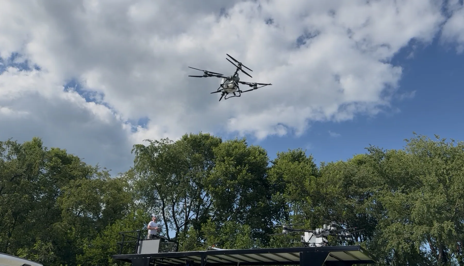 DJI Agras T100 flying above the Heavenly Acres trailer